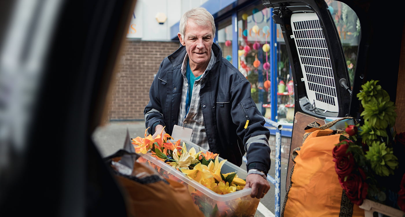 a man packing up his car with flowers